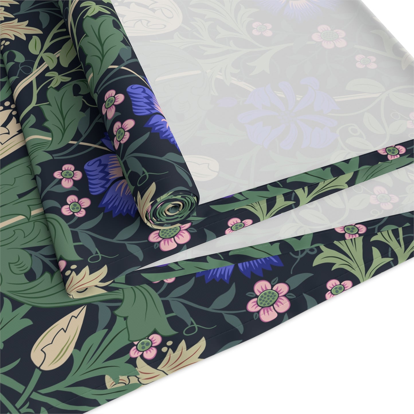 Roll of floral-patterned fabric with green leaves and pink flowers on a dark background.