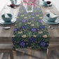 Floral patterned table runner on a wooden table with place settings.