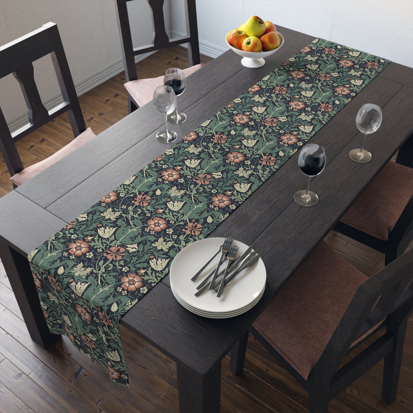 Dining table with floral table runner, plates, and glasses in a room.