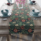 Floral patterned table runner on a wooden table with dining setup.