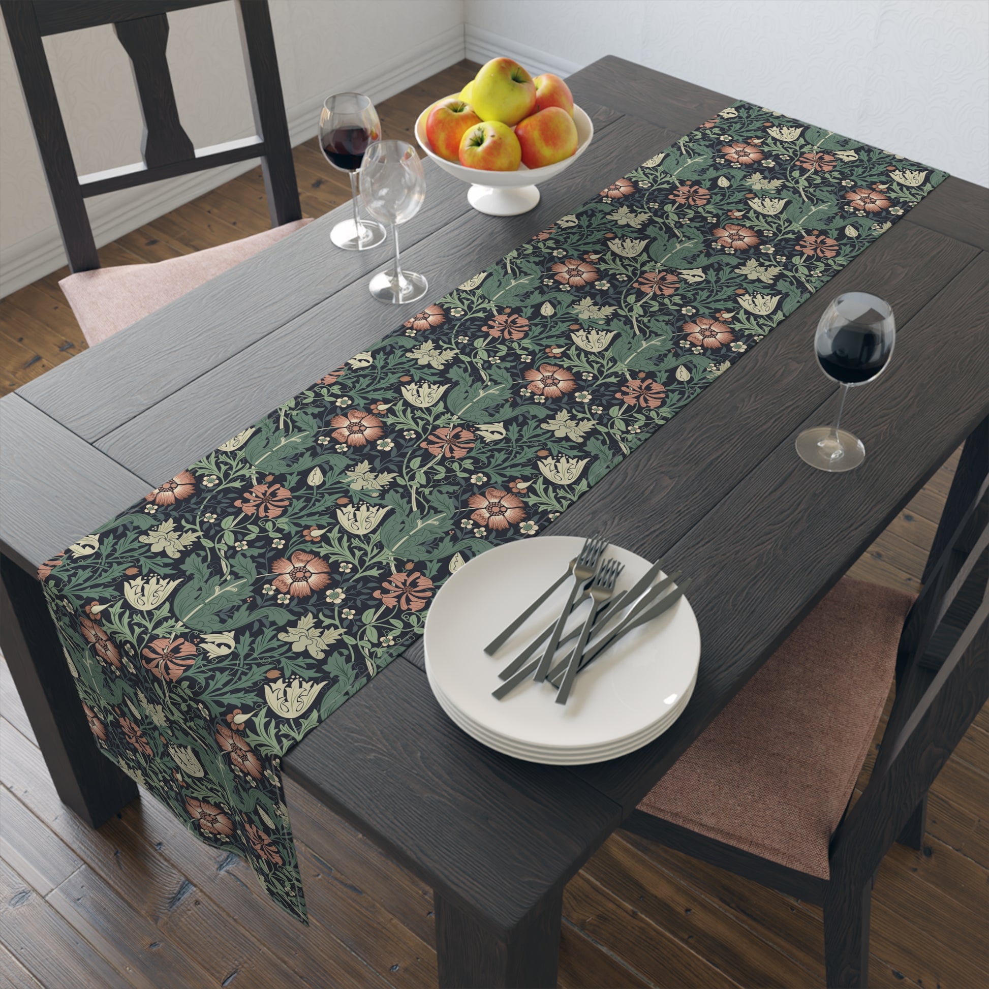 Floral patterned table runner on a wooden table with plates, forks, and wine glasses.