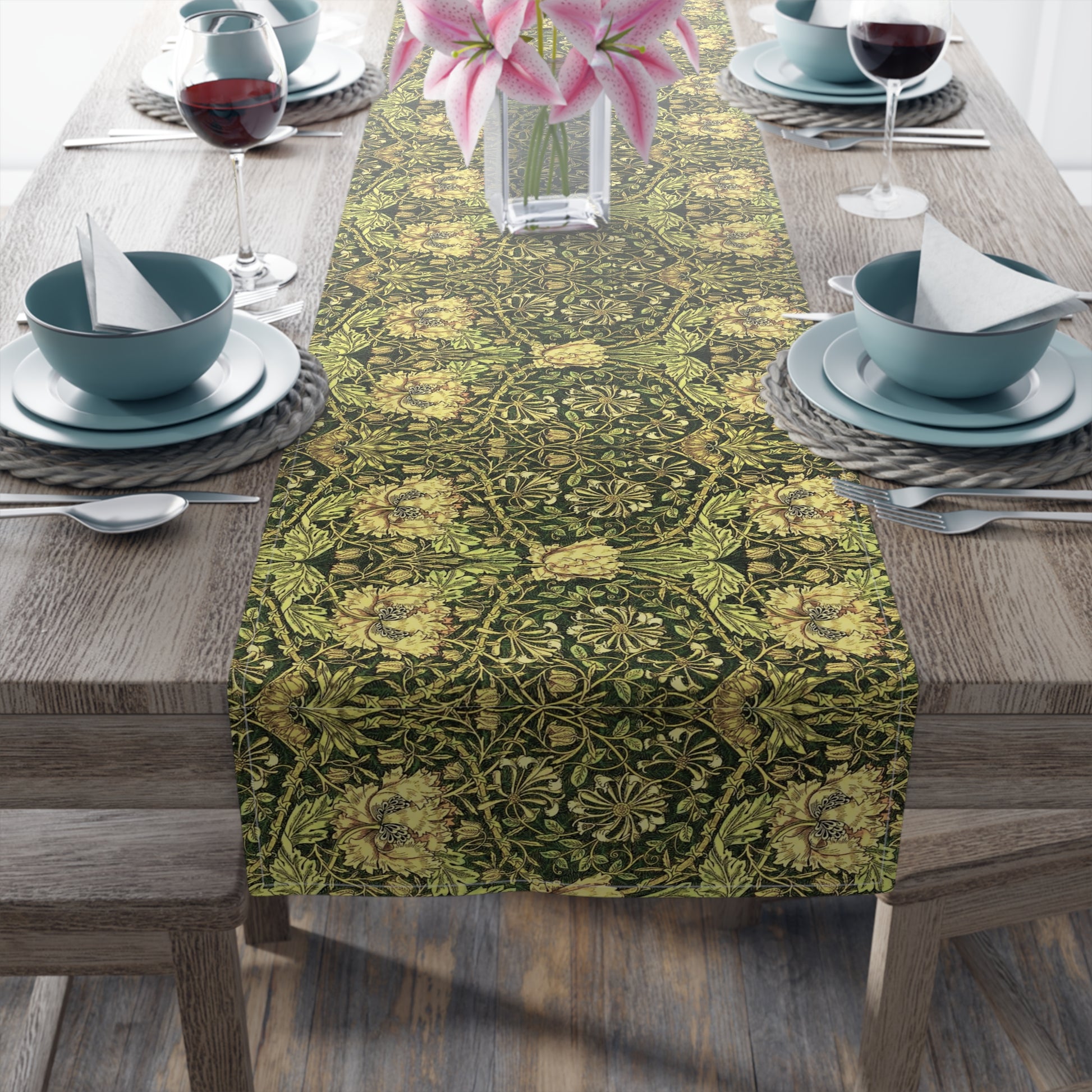 A floral patterned table runner in gold and green shades, laid out on a dining table with place settings and decorative flowers.
