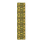 A floral patterned table runner in gold and green shades, laid out on a dining table with place settings and decorative flowers.