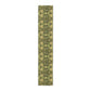 A floral patterned table runner in gold and green shades, laid out on a dining table with place settings and decorative flowers.