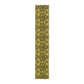 A floral patterned table runner in gold and green shades, laid out on a dining table with place settings and decorative flowers.