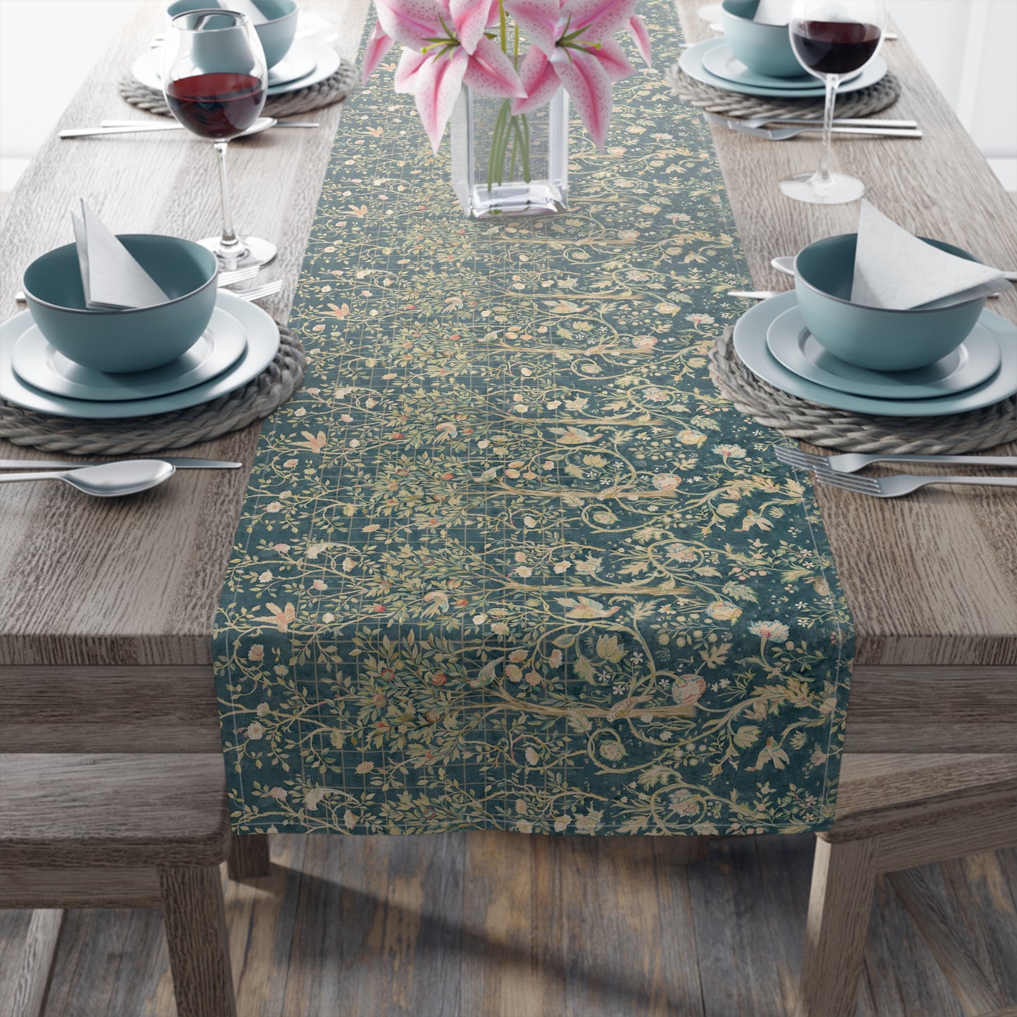 A table runner with a green and gold William Morris & Co pattern displayed on a dining table setting with dishes and glasses.