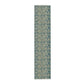 A table runner with a green and gold William Morris & Co pattern displayed on a dining table setting with dishes and glasses.