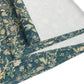 A table runner with a green and gold William Morris & Co pattern displayed on a dining table setting with dishes and glasses.