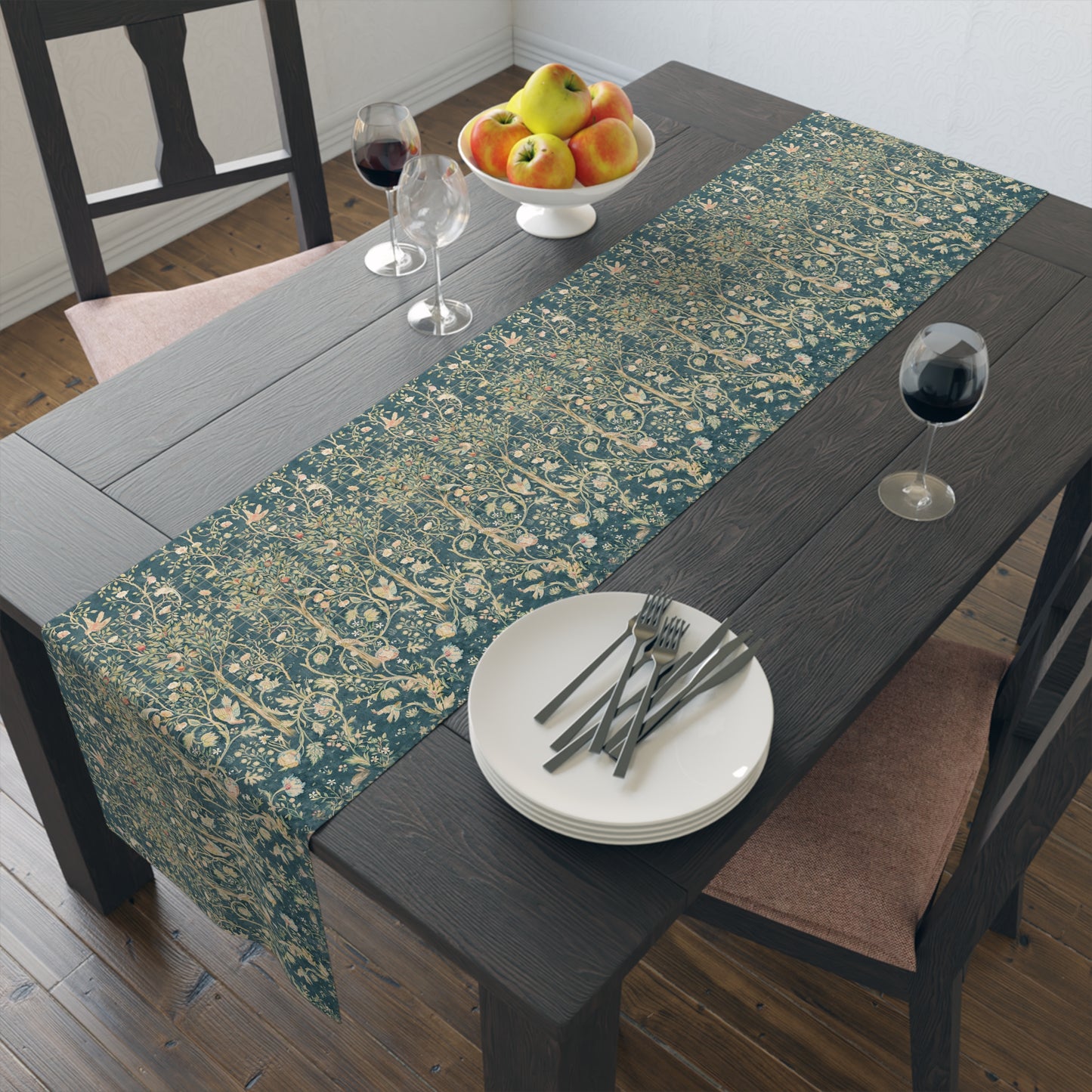 A table runner with a green and gold William Morris & Co pattern displayed on a dining table setting with dishes and glasses.