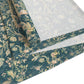 A table runner with a green and gold William Morris & Co pattern displayed on a dining table setting with dishes and glasses.