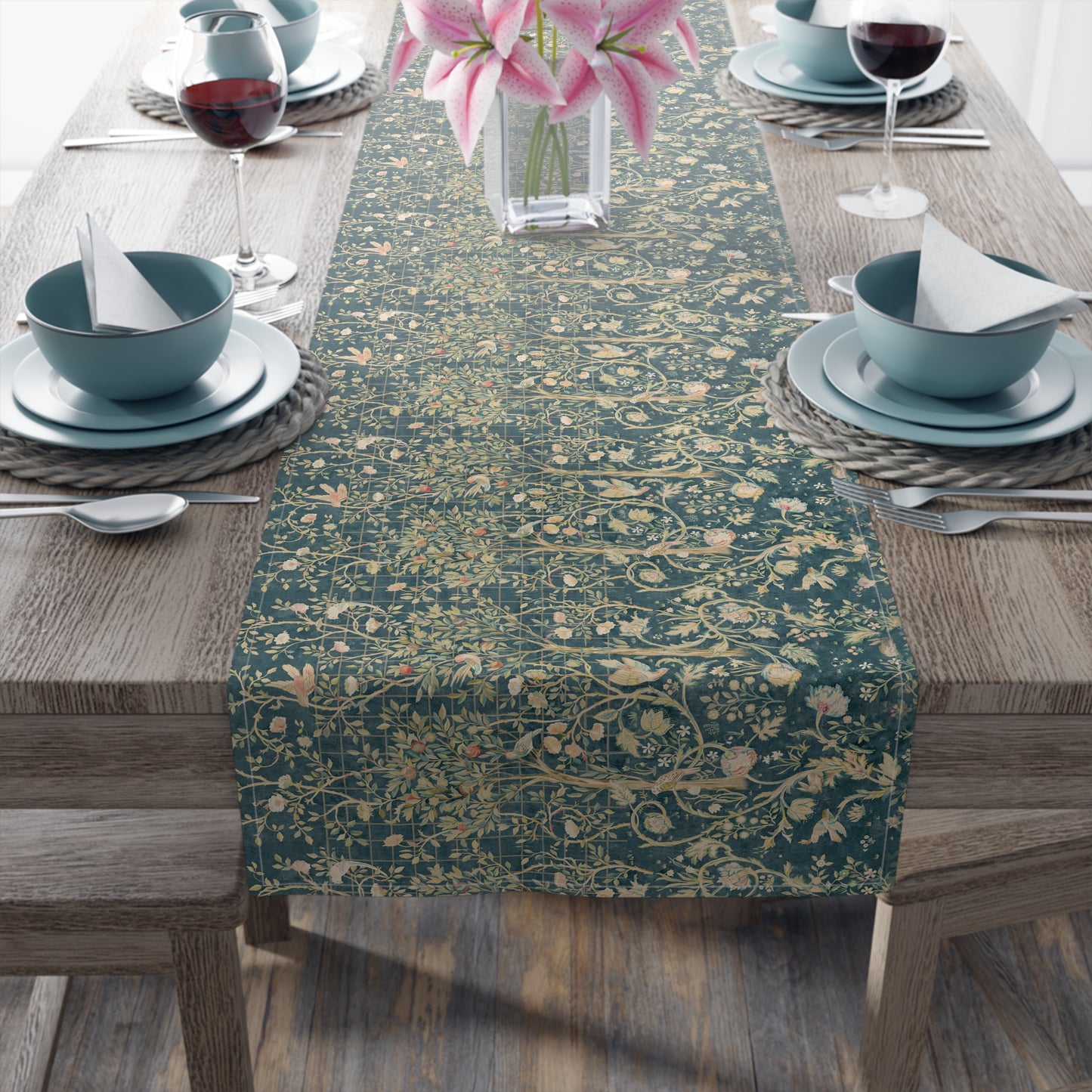 A table runner with a green and gold William Morris & Co pattern displayed on a dining table setting with dishes and glasses.