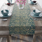 A table runner with a green and gold William Morris & Co pattern displayed on a dining table setting with dishes and glasses.