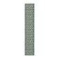 A table runner with a green and gold William Morris & Co pattern displayed on a dining table setting with dishes and glasses.