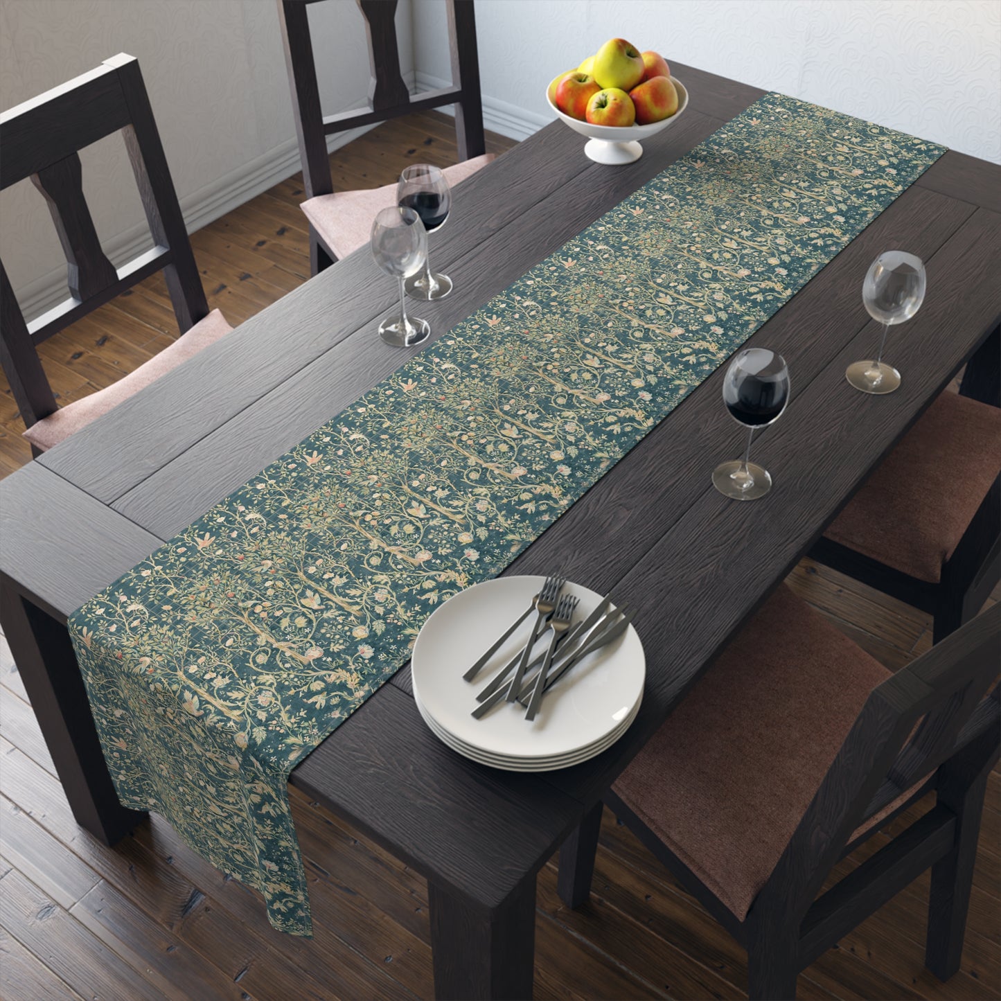 A table runner with a green and gold William Morris & Co pattern displayed on a dining table setting with dishes and glasses.