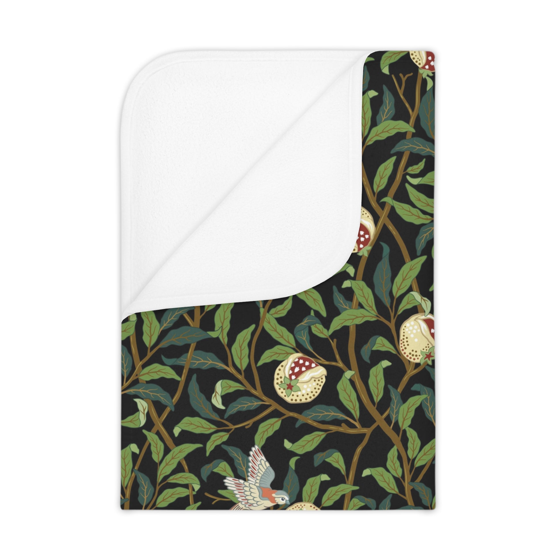 A toddler blanket with a floral pattern featuring birds and pomegranate designs in dark colors on a green background.