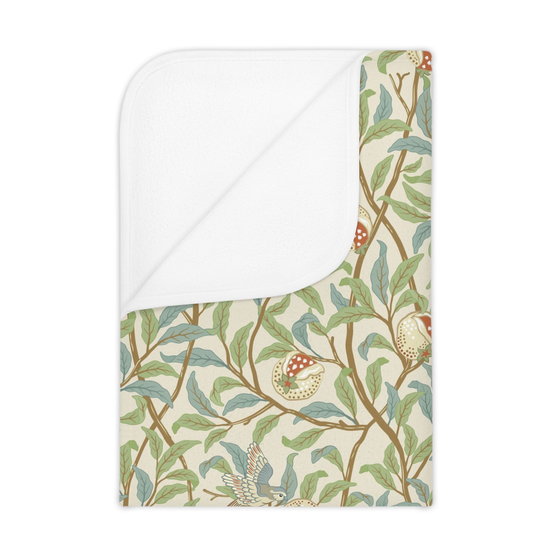 A toddler blanket with a floral pattern featuring birds and pomegranates in green, red, and beige colors on a parchment background.