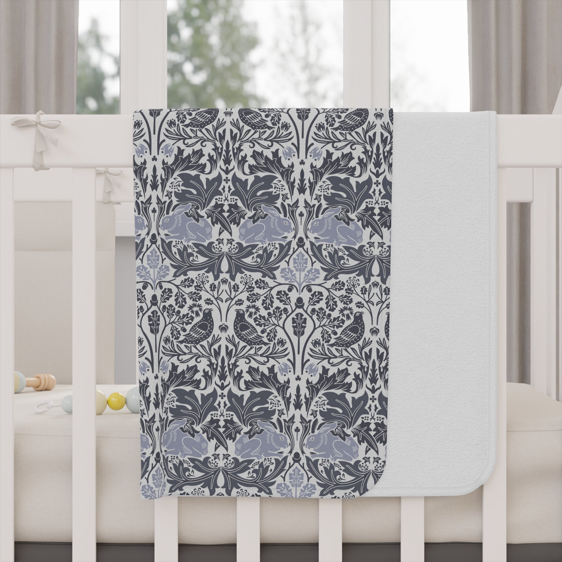 Decorative floral-patterned blanket draped over a crib in a nursery setting.