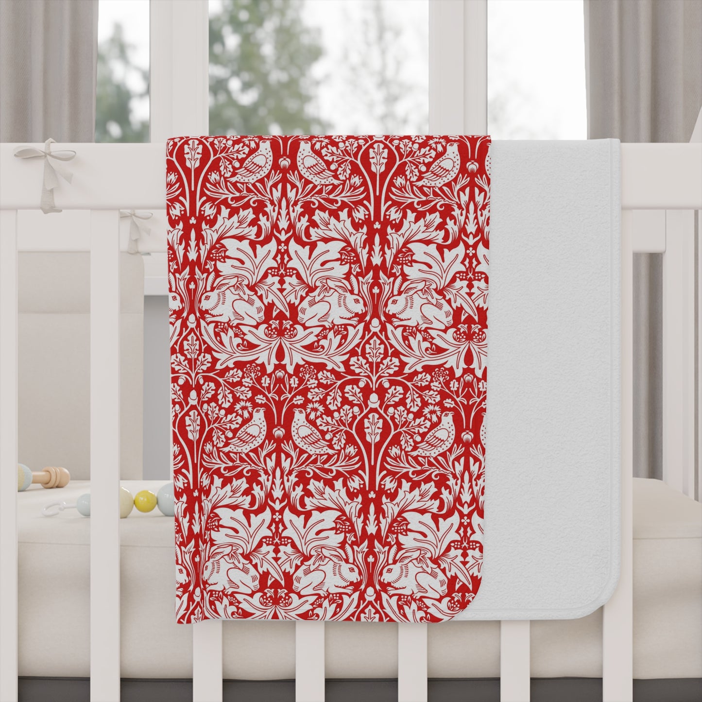 Red and white floral patterned blanket on a white crib