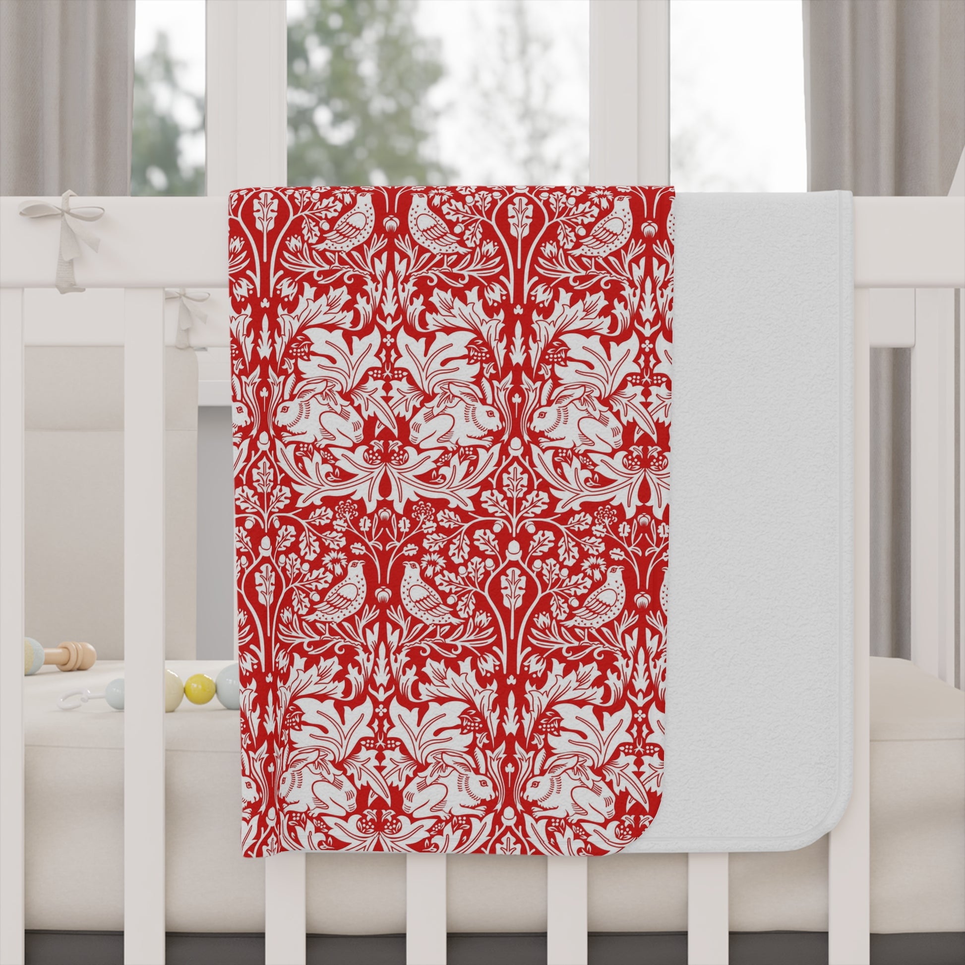 Red and white floral patterned blanket on a white crib