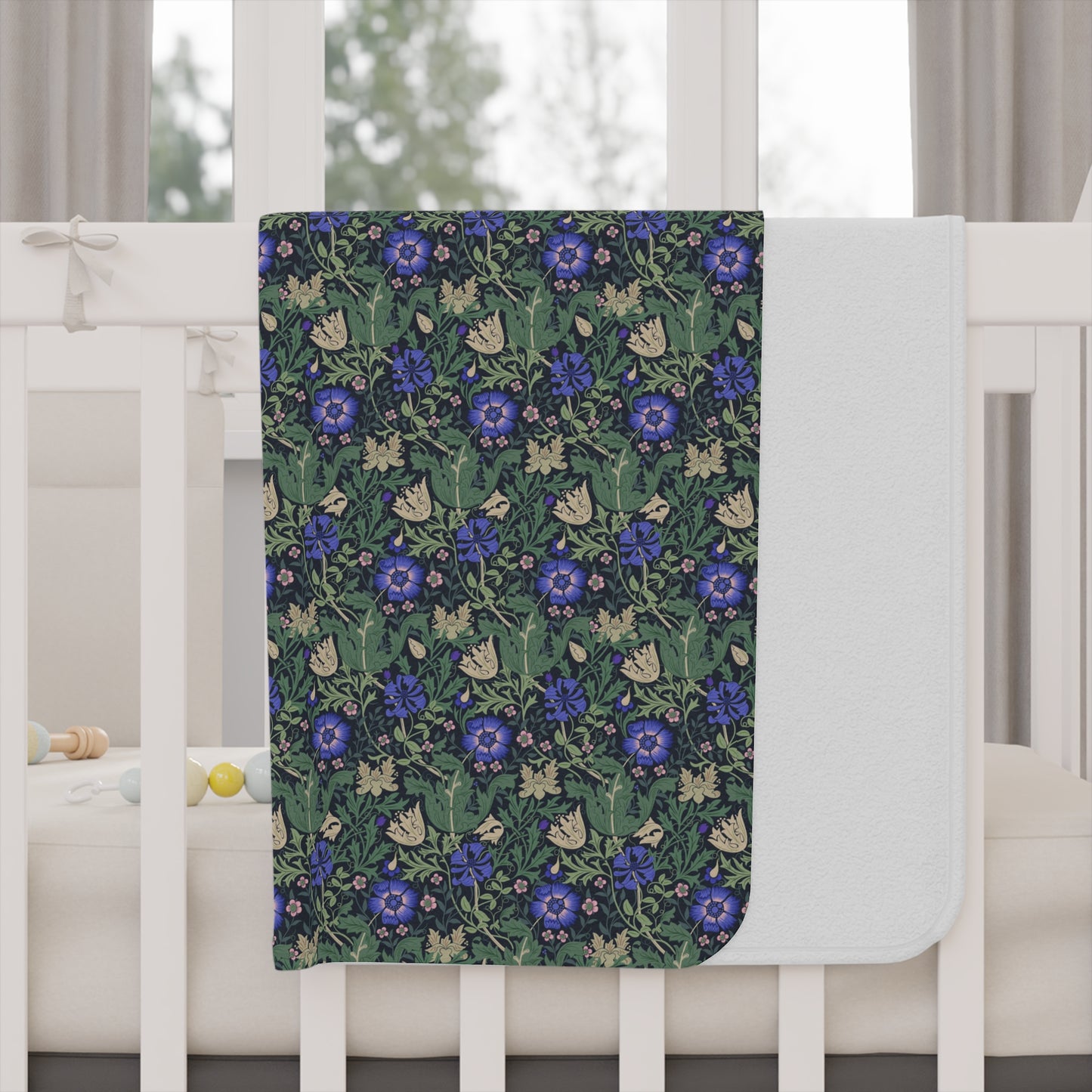 Floral patterned blanket draped over a crib with a white crib and curtains in the background.