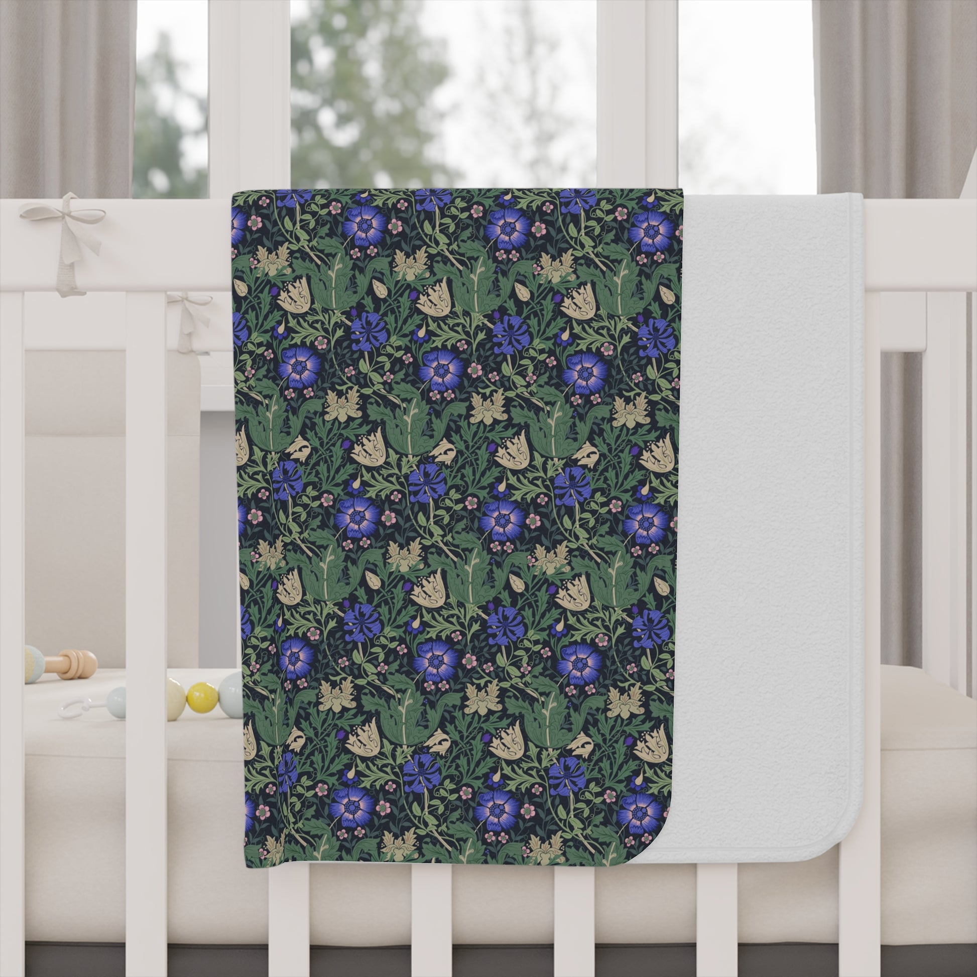 Floral patterned blanket draped over a crib with a white crib and curtains in the background.