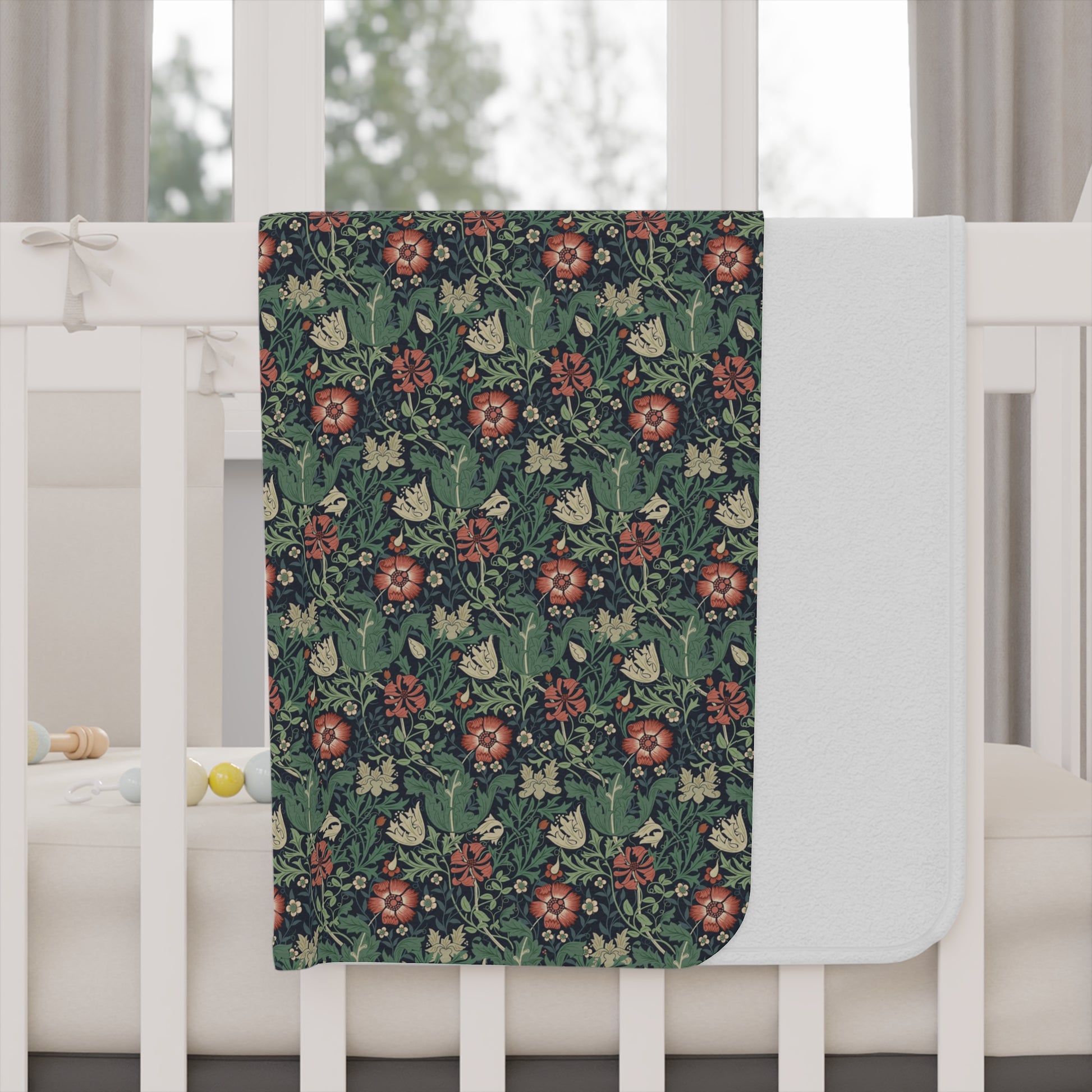 Floral patterned blanket draped over a crib with a white crib and curtains in the background.