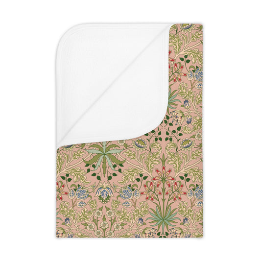 A toddler blanket with a floral pattern inspired by William Morris, in shades of green, pink, and blue on a beige background.