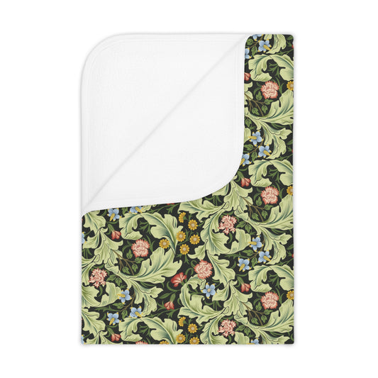 A toddler blanket with a floral pattern in green, inspired by William Morris' Leicester Collection.