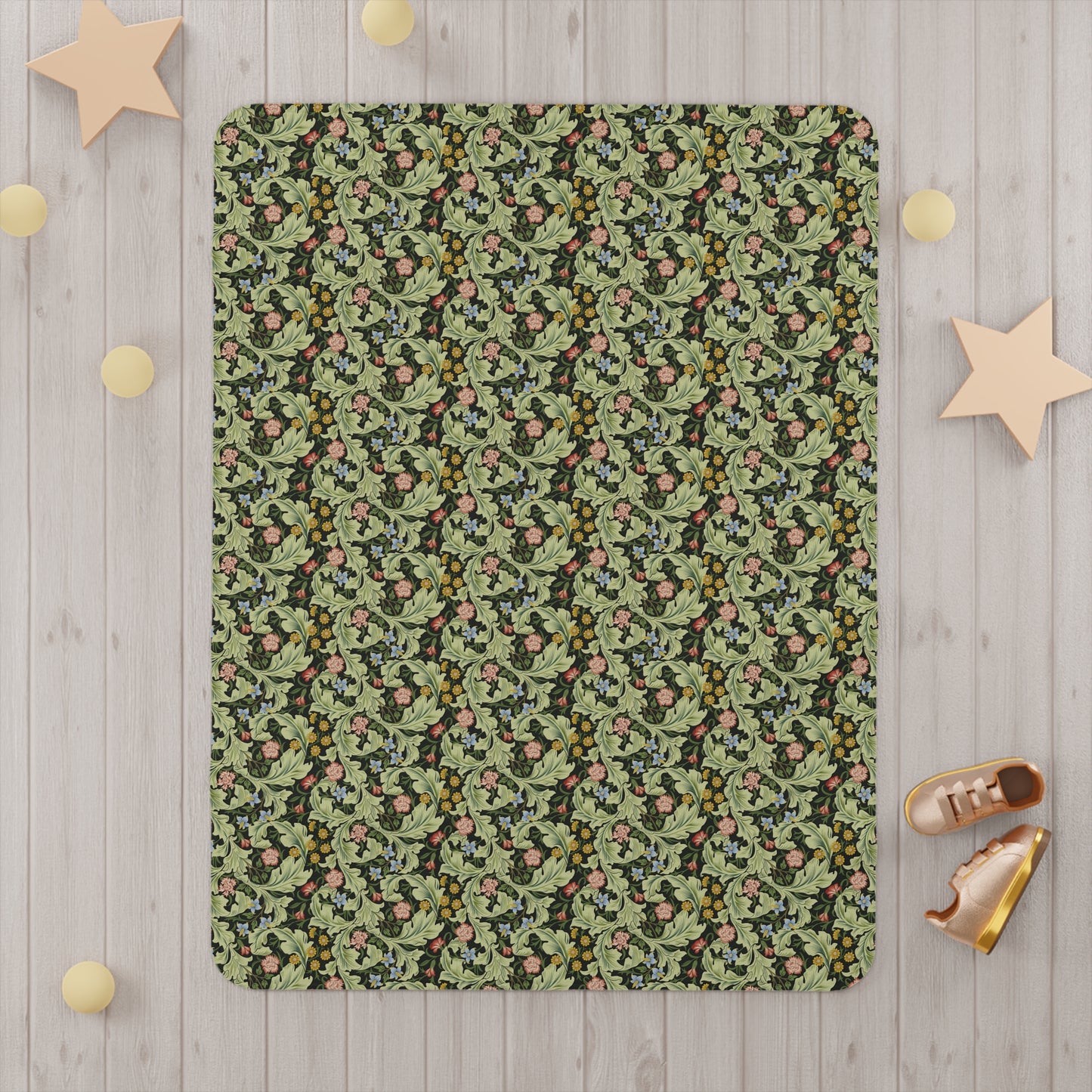 A toddler blanket with a floral pattern in green, inspired by William Morris' Leicester Collection.