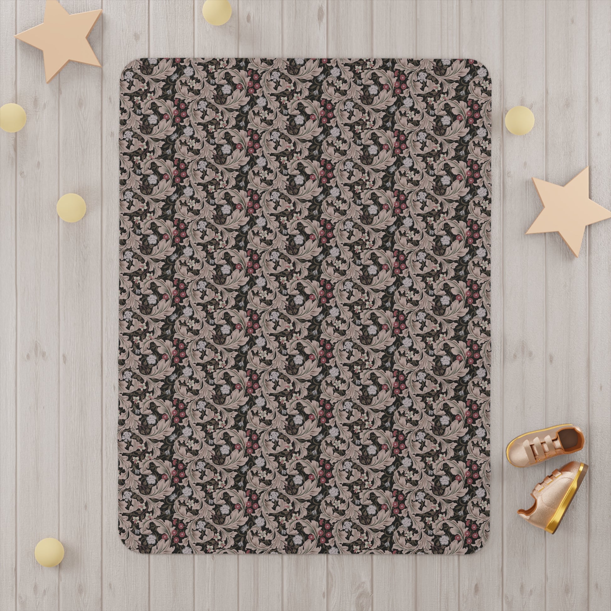 A toddler blanket with a floral pattern inspired by William Morris, in mocha and white colours, folded neatly.