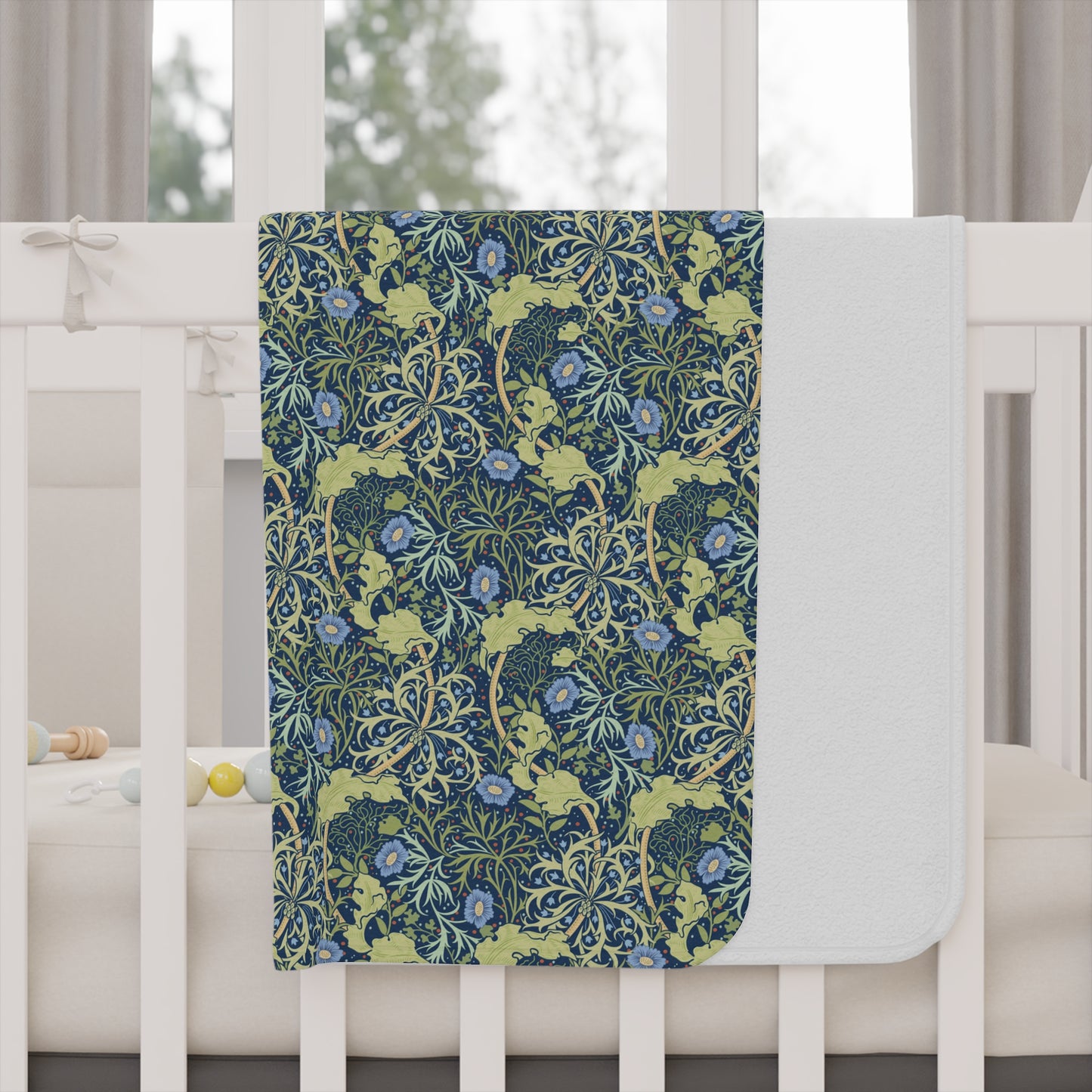 Floral patterned blanket draped over a crib with a white crib and curtains in the background.