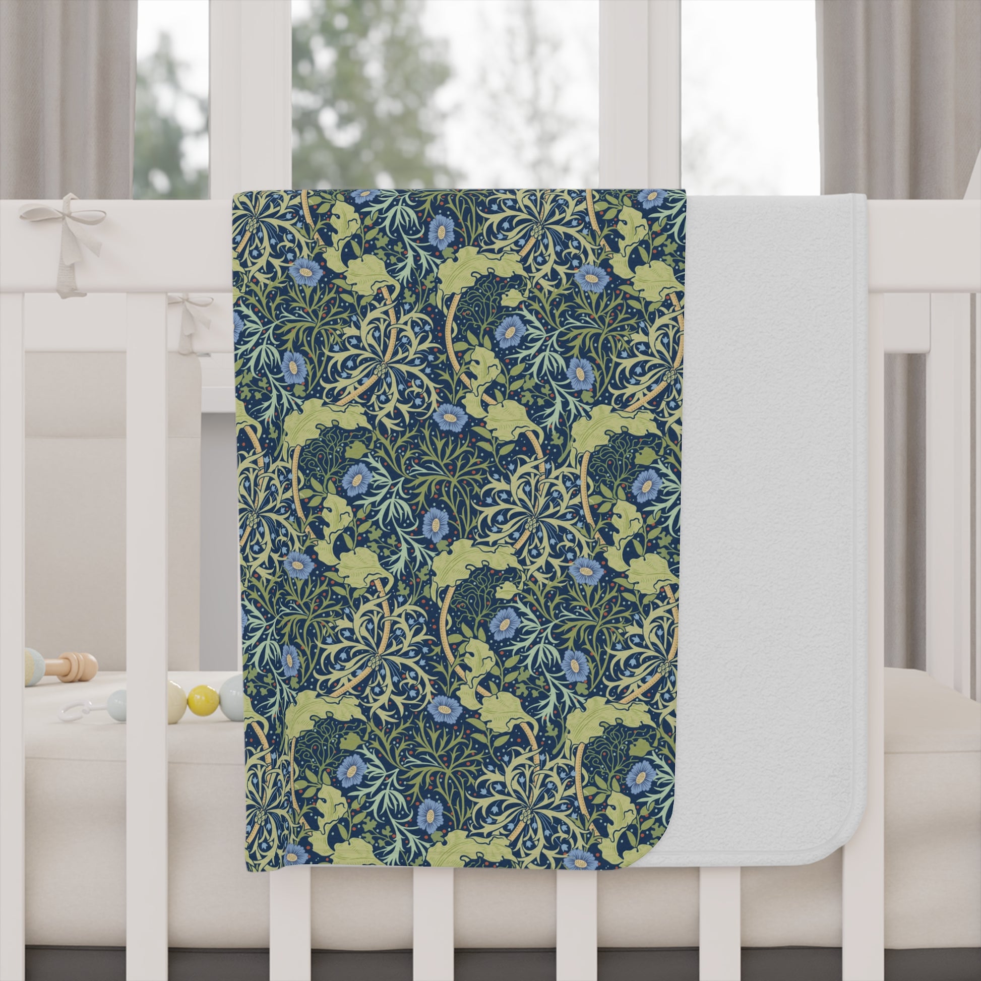 Floral patterned blanket draped over a crib with a white crib and curtains in the background.