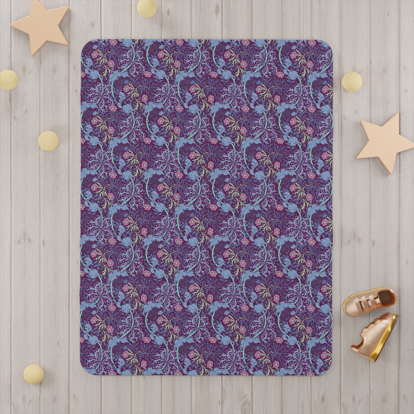 Purple patterned blanket on a wooden floor with decorative stars and shoes around it.