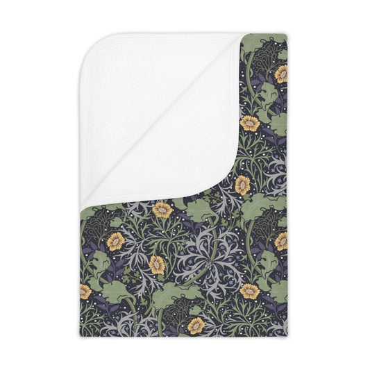 A toddler blanket with a floral pattern inspired by William Morris, featuring yellow flowers on a green background, folded to show both sides.