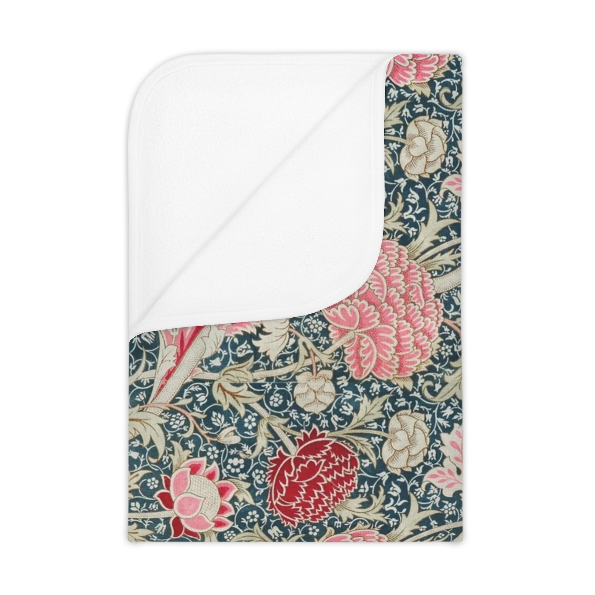 Floral William Morris & Co patterned blanket draped over a crib with a white crib and curtains in the background.