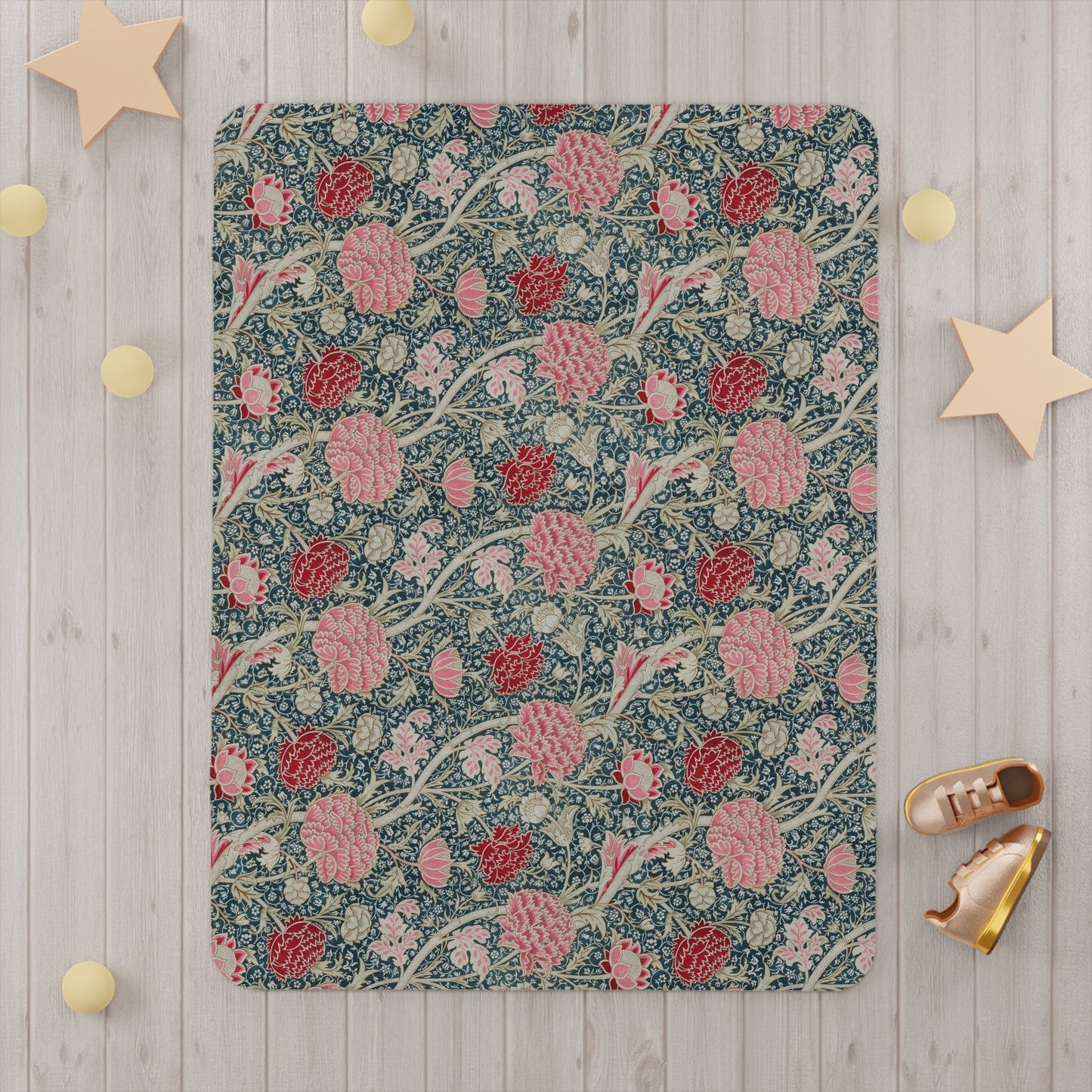 Floral William Morris & Co patterned blanket draped over a crib with a white crib and curtains in the background.