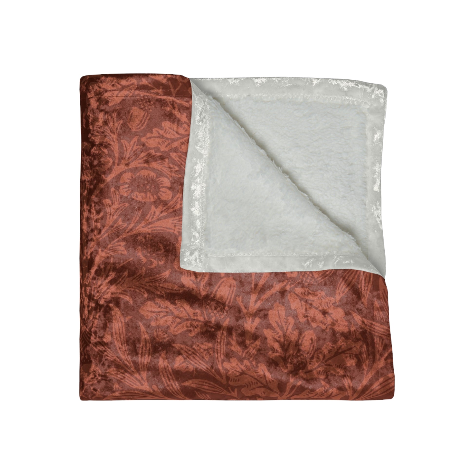 A crushed velvet blanket in a rust colour, with a pattern inspired by William Morris' acorns and oak leaves, displayed folded with the reverse side partially visible.
