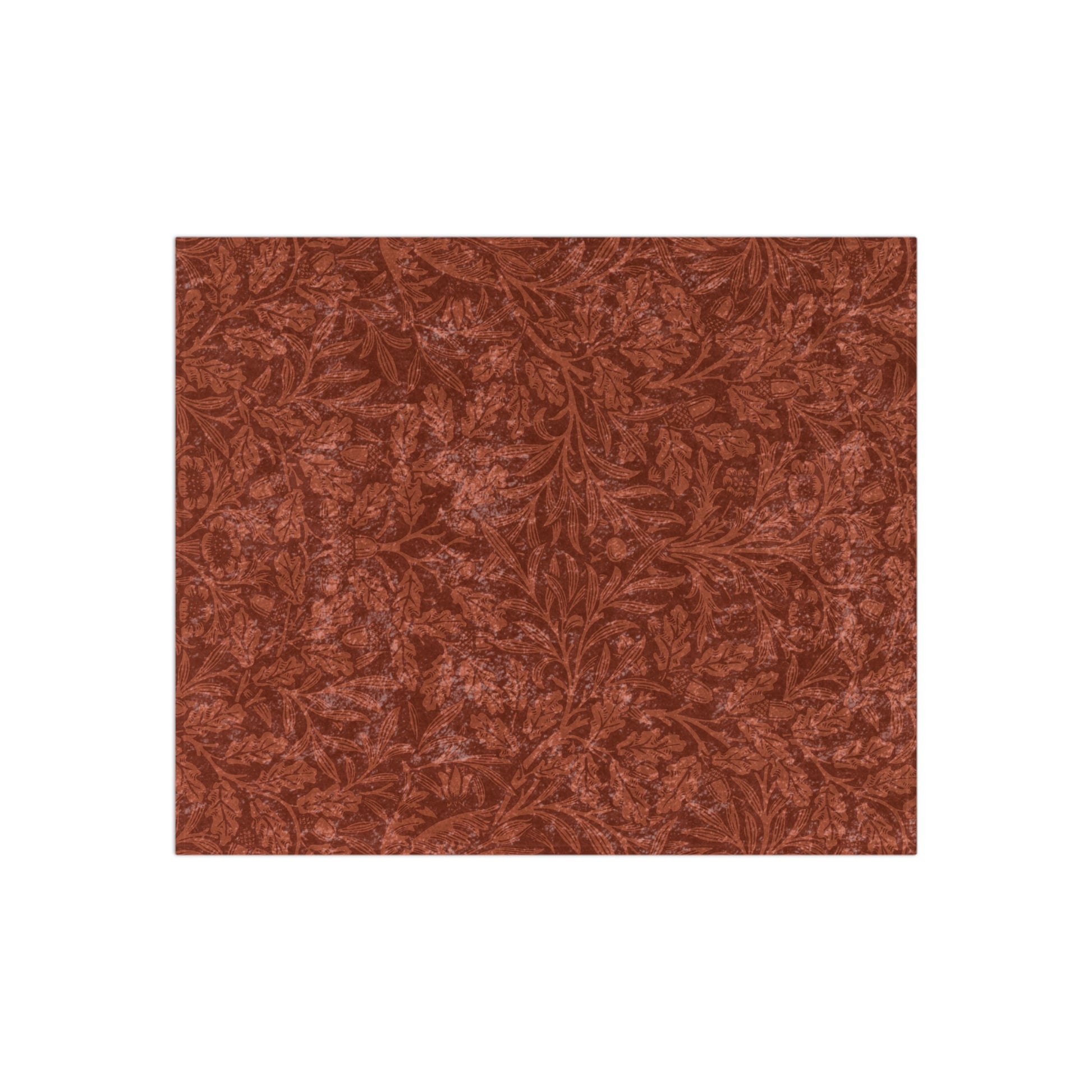 A crushed velvet blanket in a rust colour, with a pattern inspired by William Morris' acorns and oak leaves, displayed folded with the reverse side partially visible.