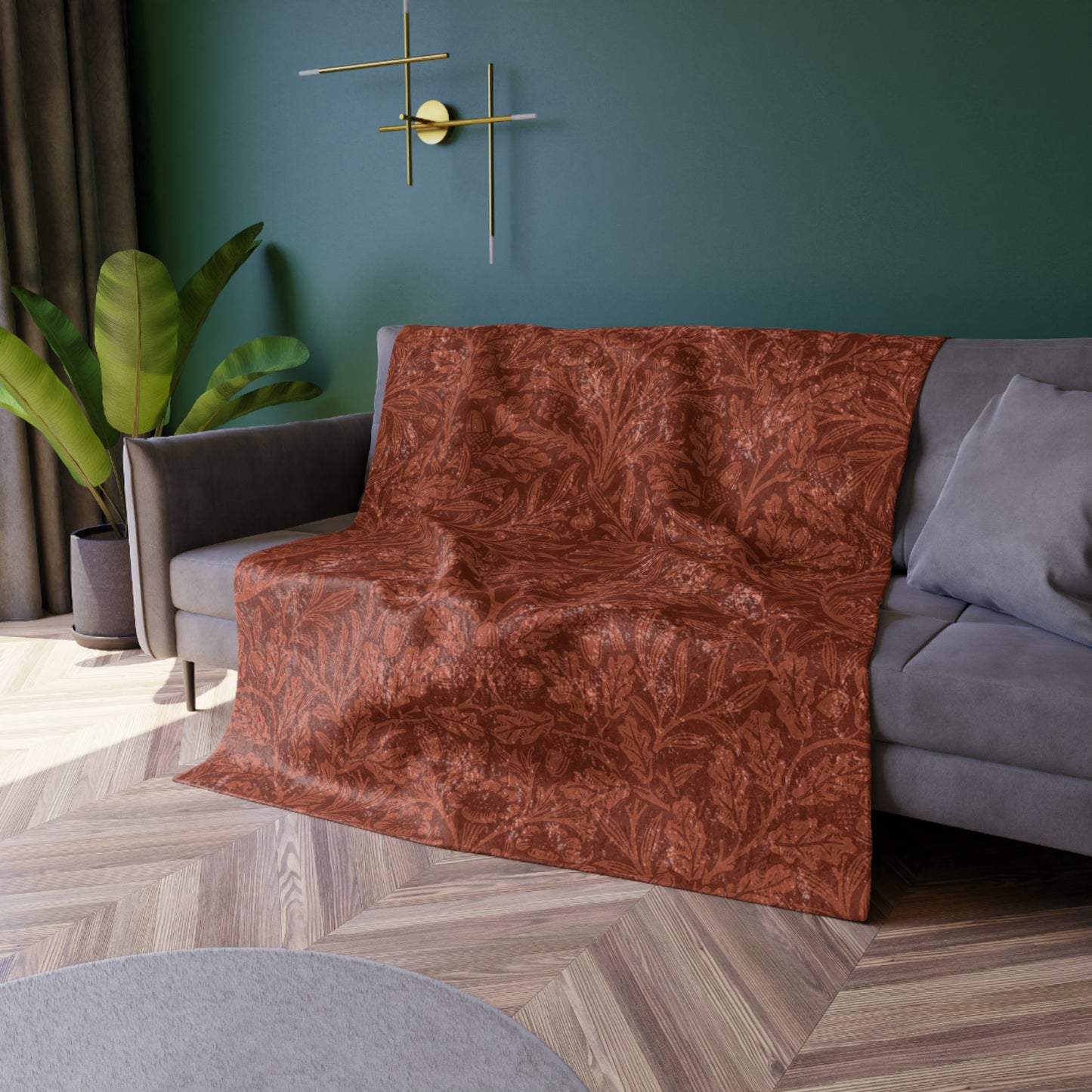 A crushed velvet blanket in a rust colour, with a pattern inspired by William Morris' acorns and oak leaves, displayed folded with the reverse side partially visible.