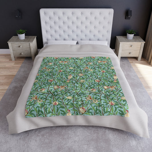 A crushed velvet blanket with a floral pattern in shades of blue and green, featuring birds and pomegranate designs, displayed on a flat surface.