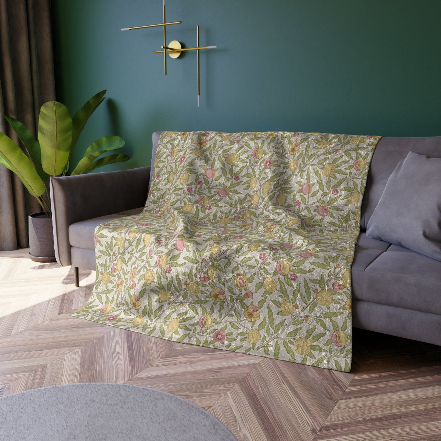 Floral-patterned blanket draped over a sofa in a living room with a green wall and plant.
