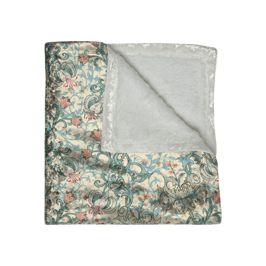 A plush velvet blanket with a floral pattern in a mineral colour palette, folded neatly to show both the patterned side and the silky reverse.