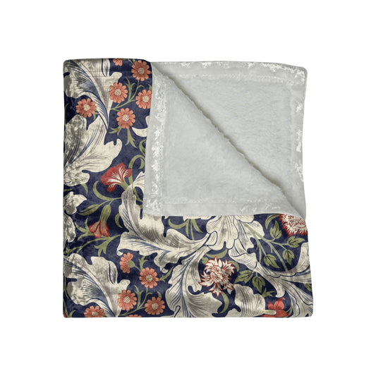 A lush crushed velvet blanket with a floral William Morris & Co pattern in shades of blue, red, and white, hemmed edges, and a silky finish.