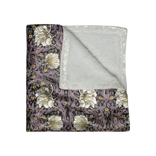 A plush velvet blanket with a William Morris & Co floral pattern in shades of purple and green, displaying a silky finish and hemmed edges.