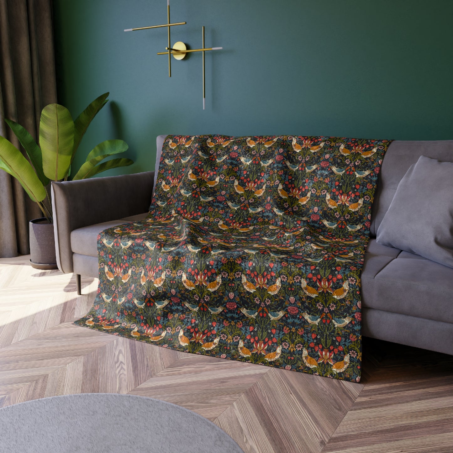 Gray sofa with a colorful floral patterned throw blanket in a room with green walls and wooden flooring.