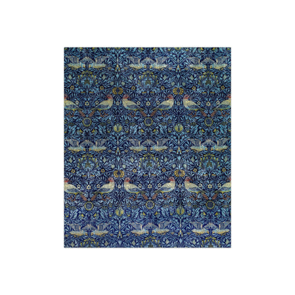 A lush crushed velvet blanket with a blue floral pattern on the surface and a silky finish, hemmed edges, and a white interior visible at one end.