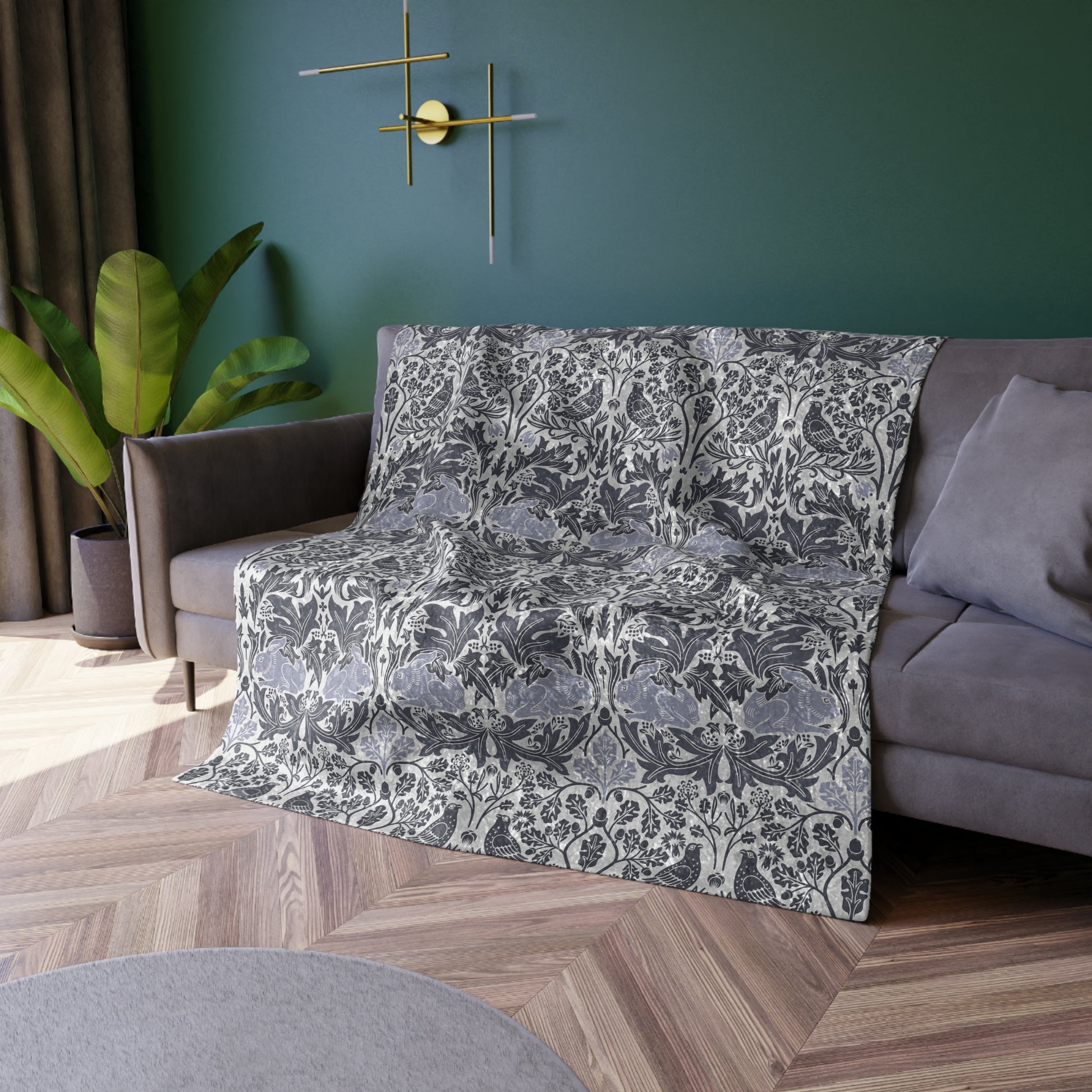 Floral-patterned throw blanket draped over a sofa in a living room with green walls and a plant.