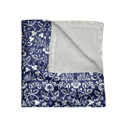 A crushed velvet blanket with a floral William Morris & Co pattern in a navy blue colour on a white background, hemmed edges, and a silky finish.