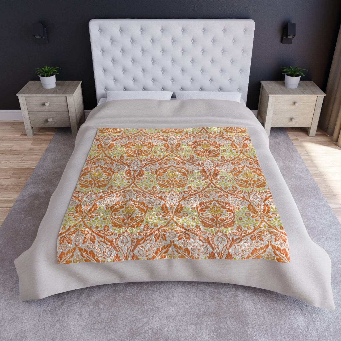 A crushed velvet blanket with a William Morris & Co floral pattern in shades of orange, yellow, and green on a white background, folded to show both the patterned side and the solid silky finish.