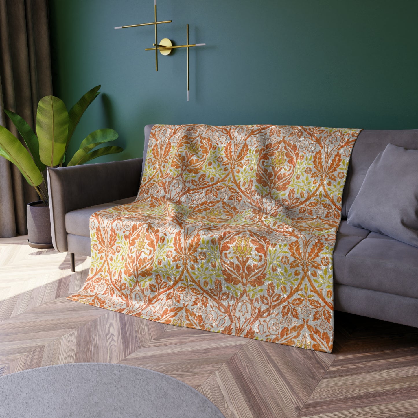 A crushed velvet blanket with a William Morris & Co floral pattern in shades of orange, yellow, and green on a white background, folded to show both the patterned side and the solid silky finish.